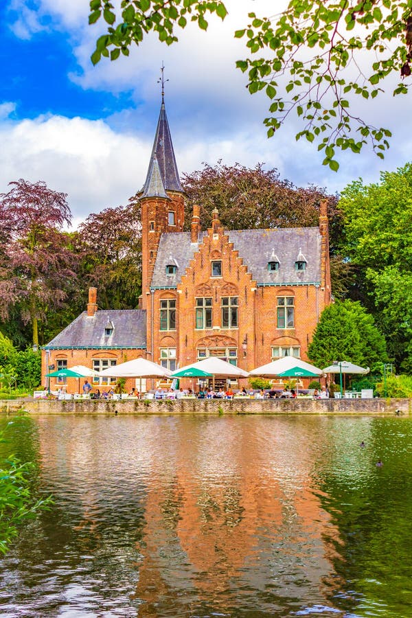 Minnewater castle with people enjoying the view at the outdoor restaurant seating by the Lake of Love in Bruges, Belgium, fairytale scenery in Bruges. Bruges Brugge historic city is a prominent World Heritage Site of UNESCO.August 7th 2016. Minnewater castle with people enjoying the view at the outdoor restaurant seating by the Lake of Love in Bruges, Belgium, fairytale scenery in Bruges. Bruges Brugge historic city is a prominent World Heritage Site of UNESCO.August 7th 2016