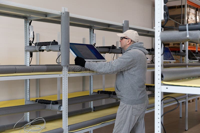 Minsk, Belarus - Dec 15, 2021: Photo of a man in a gray suit checking the computer at work. Testing. Engineer at a modern high-tech factory.