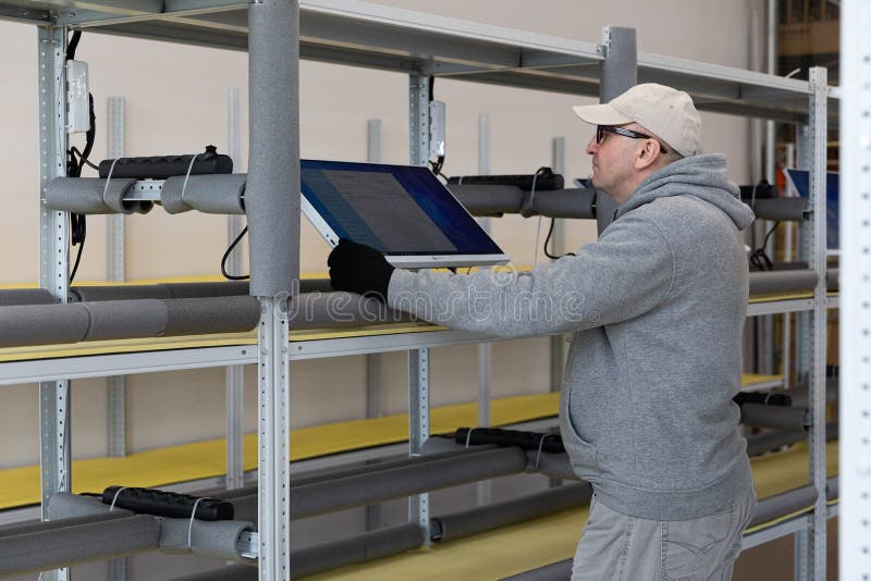Minsk, Belarus - Dec 15, 2021: Photo of a man in a gray suit checking the computer at work. Testing. Engineer at a modern high-tech factory.