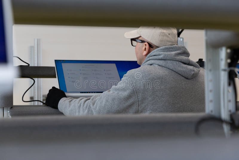 Minsk, Belarus - Jan 05, 2022: Photo of a man in a gray suit checking the computer at work. Testing. Engineer at a modern high-tech factory.