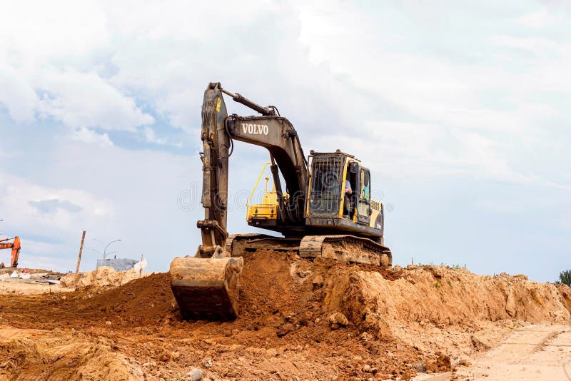 MINSK, BELARUS - July 2, 2021: Bright yellow heavy industrial excavator working on construction site in the city.