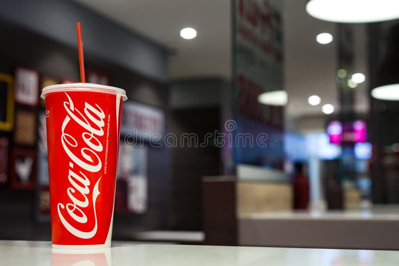 MINSK, październik 30, 2017: Papierowa filiżanka koka-kola na cukiernianym stole zdjęcia stock MINSK, październik 30, 2017: Papierowa filiżanka koka-kola na cukiernianym stole zdjęcia stock