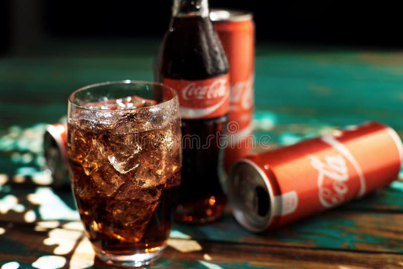 MINSK, 25 WITRUSSISCH-AUGUSTUS, 2016 Kan en een glas van bevroren Coca-Cola op een houten lijst stock afbeelding MINSK, 25 WITRUSSISCH-AUGUSTUS, 2016 Kan en een glas van bevroren Coca-Cola op een houten lijst stock afbeelding
