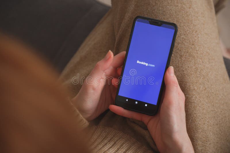 Minskbelarus : 27 maja 2020 r. : widok na smartphone z logo rezerwacji w rękach kobiet. koncepcja mediów społecznościowych zdjęcia stock
