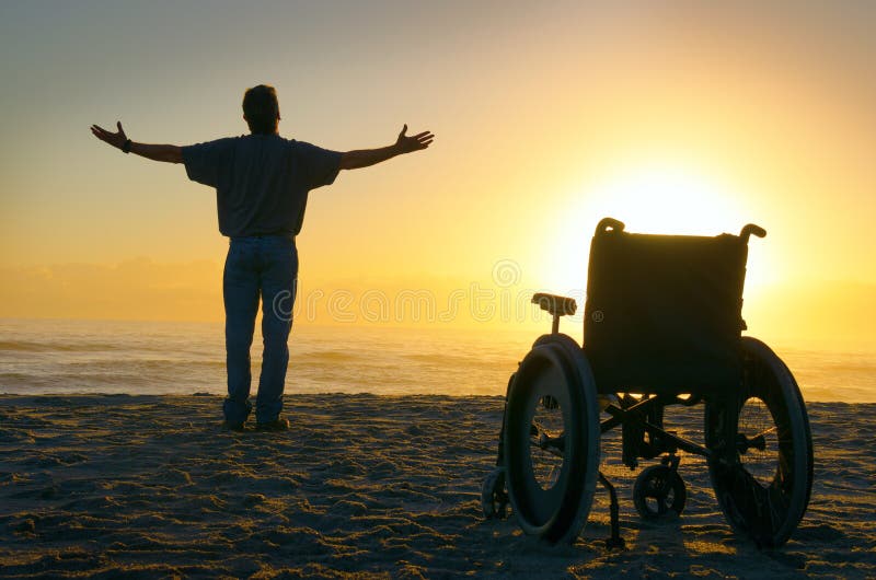 Zázrak duchovní léčení zmrzačený muž vysoký paže rozšířit na oceán pobřeží jako on stojany nahoru ven z jeho invalidní vozík a procházky k východ slunce.
