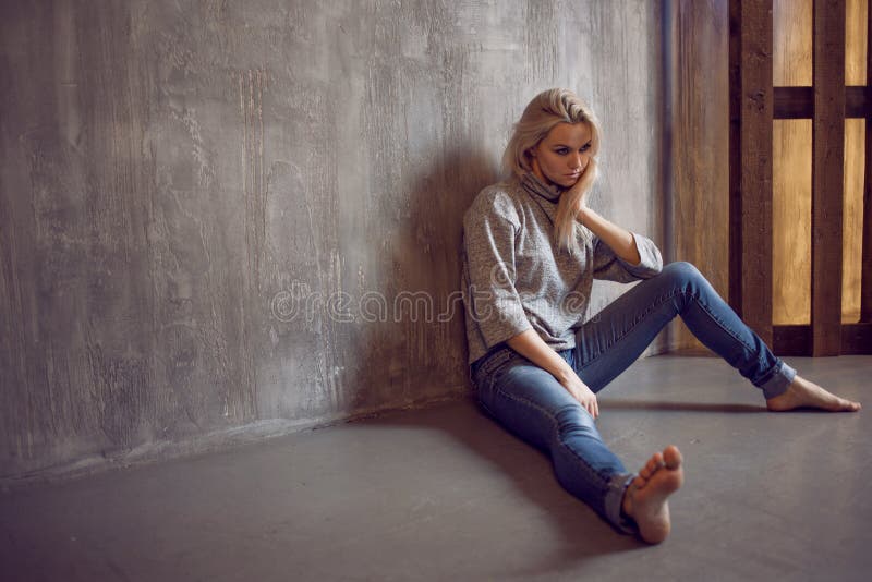 Mirada de la mujer muchacha rubia que se sienta en el piso, la tristeza y la depresión fotografía de archivo libre de regalías Mirada de la mujer muchacha rubia que se sienta en el piso, la tristeza y la depresión fotografía de archivo libre de regalías