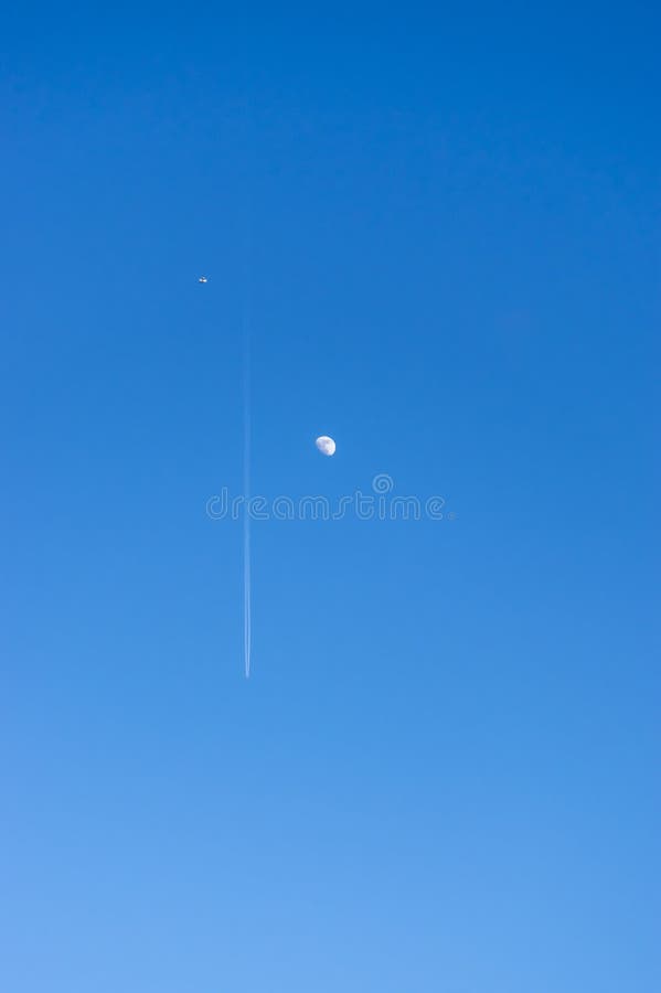 Mirada para arriba en el cielo azul y despejado brillante con la luna y un avión de pasajeros con estelas de vapor y un pequeño a fotografía de archivo Mirada para arriba en el cielo azul y despejado brillante con la luna y un avión de pasajeros con estelas de vapor y un pequeño a fotografía de archivo