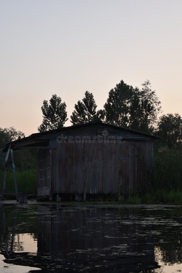 Mirada rústica de una casa vieja hecha de la lata con el fondo del cielo de la puesta del sol en el medio del lago Dal, Srinagar, fotografía de archivo Mirada rústica de una casa vieja hecha de la lata con el fondo del cielo de la puesta del sol en el medio del lago Dal, Srinagar, fotografía de archivo