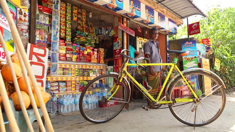 MIRISSA SRI LANKA - MARS 2014: Cykla parkerat utanför en lokal shoppar med mananseende i bakgrund på gatan i Mirissa