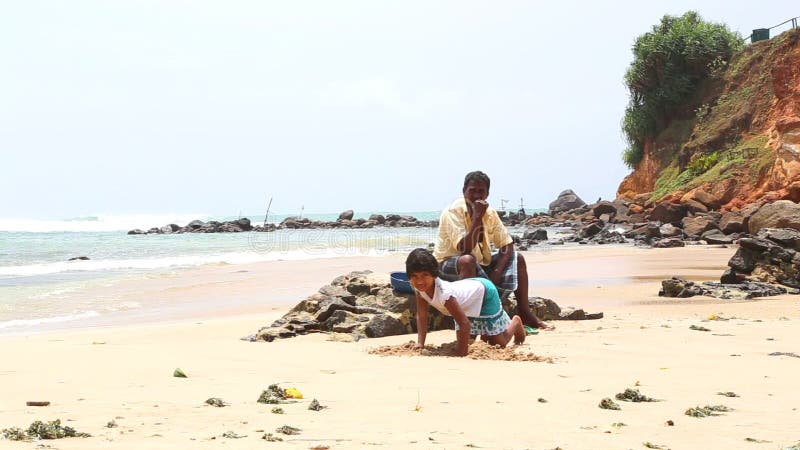 MIRISSA SRI LANKA - MARS 2014: Liten flicka som spelar på stranden i Mirissa Denna lilla sandiga tropiska strand skryter någon av