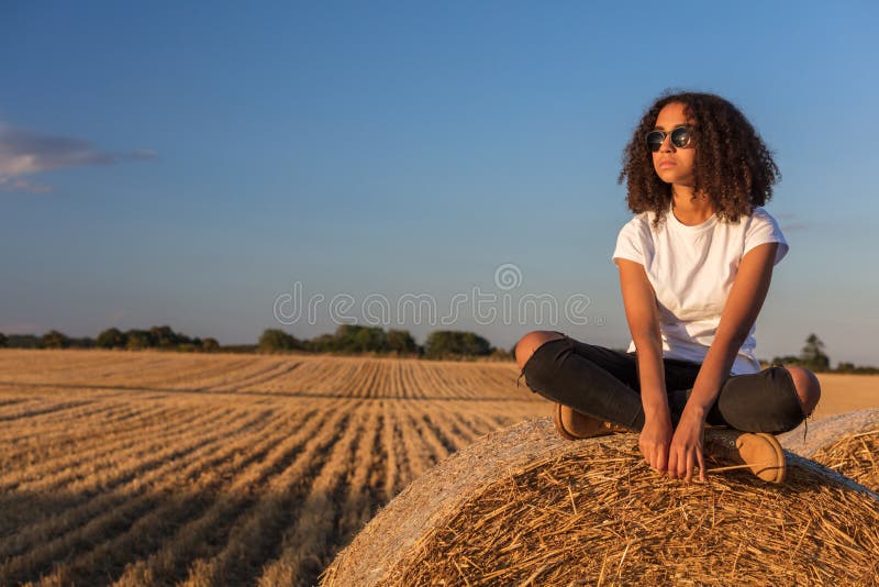 Mischrasse-Afroamerikaner-Mädchen-jugendlich Sonnenbrille, die auf Heu sitzt stockfoto