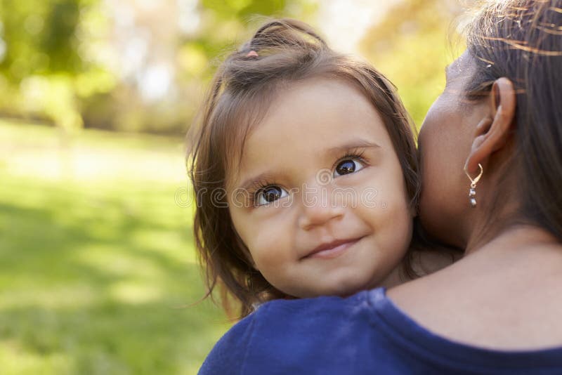 Mischrassemutter, die ihre Tochter, über Schulteransicht hält lizenzfreies stockfoto Mischrassemutter, die ihre Tochter, über Schulteransicht hält lizenzfreies stockfoto