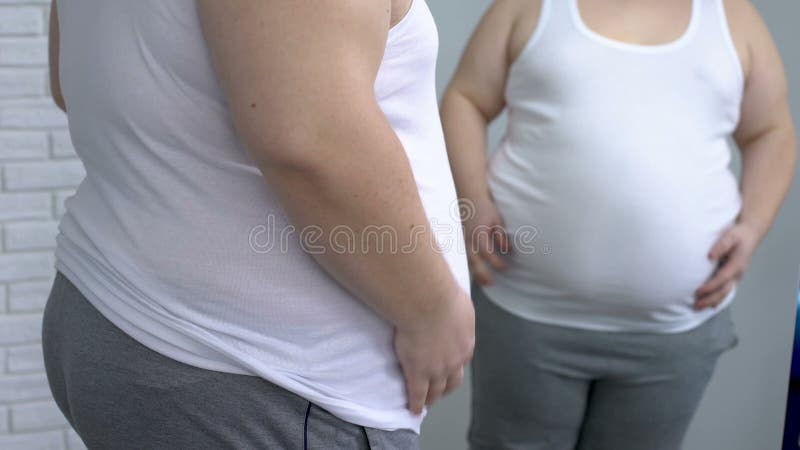 Mise masculine obèse sur la chemise blanche devant le miroir, désir de perdre le poids