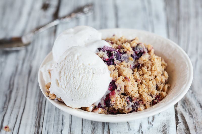 Blackberry and Blueberry Cobbler topped with a golden oatmeal crisp with ice cream. Extreme selective focus with blurred background. Blackberry and Blueberry Cobbler topped with a golden oatmeal crisp with ice cream. Extreme selective focus with blurred background