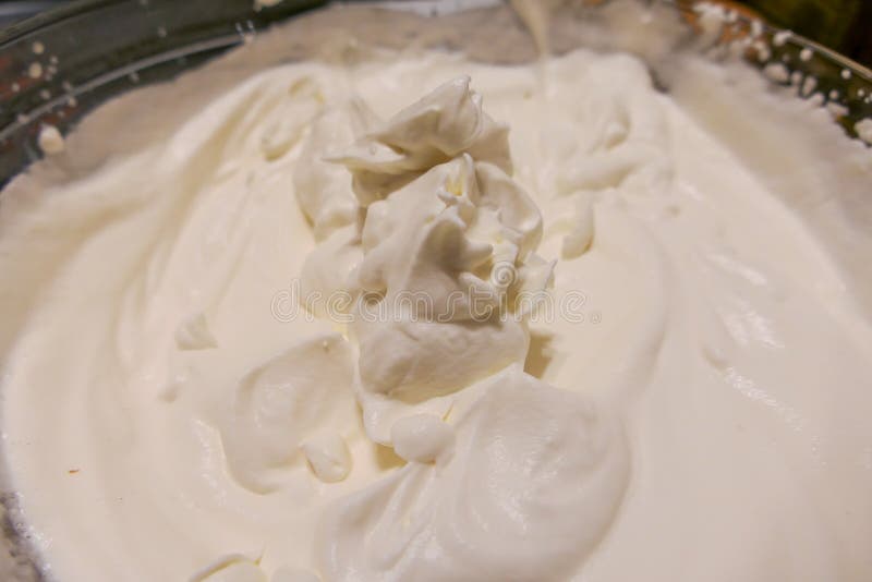 A large mixing bowl is filled with freshly made whipped cream.  The photo is taken from above and is a close up. A large mixing bowl is filled with freshly made whipped cream.  The photo is taken from above and is a close up.