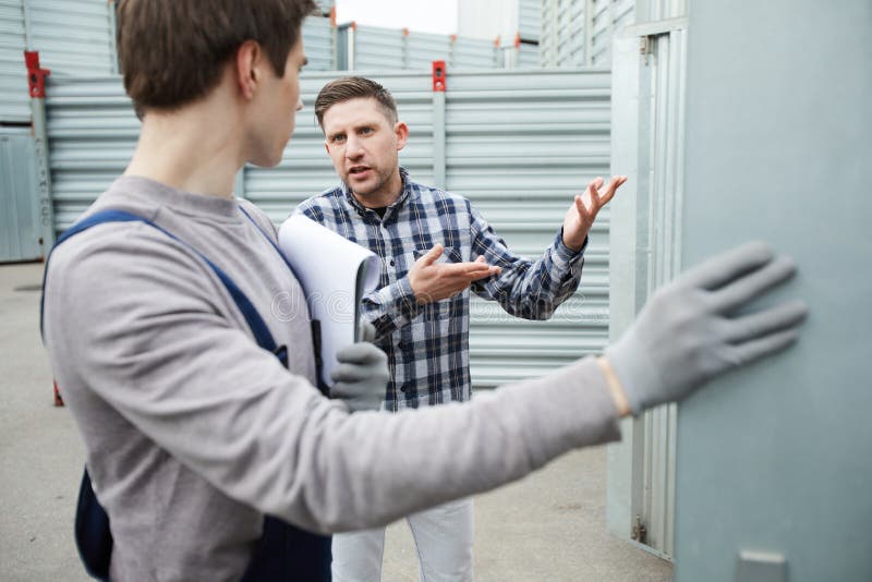 Missförståndklient som talar till lagringsarbetaren arkivbild