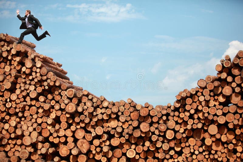 Mission accomplished - running business man on top of large pile of logs. Mission accomplished - running business man on top of large pile of logs