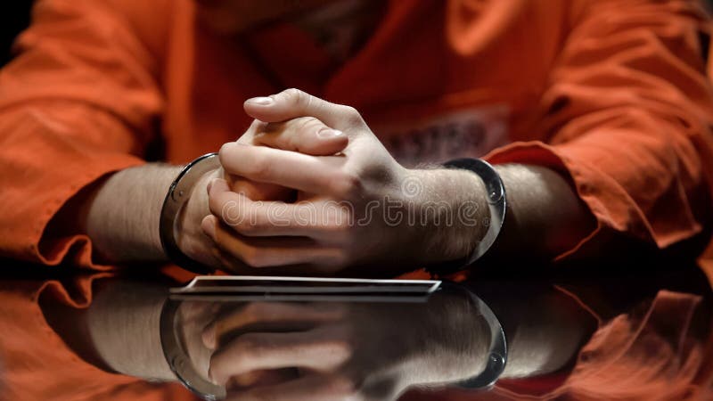 Misstänkt i handbojor som håller ögonen på fotoet som samarbetar med polisen i utredning arkivfoto Misstänkt i handbojor som håller ögonen på fotoet som samarbetar med polisen i utredning arkivfoto