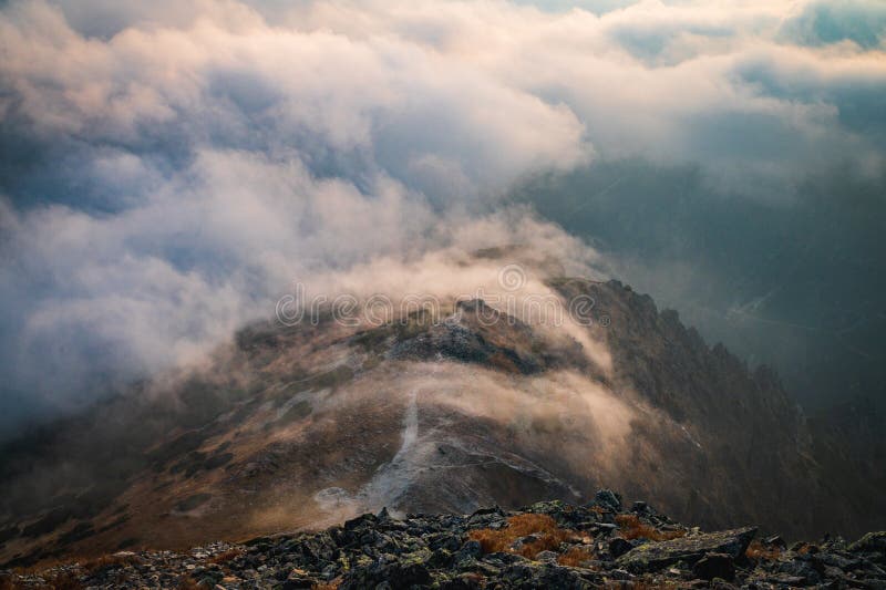 Mlha a mlha nad vrcholem kopce v horách večerní oranžové světlo. podzimní nálada v kopcích