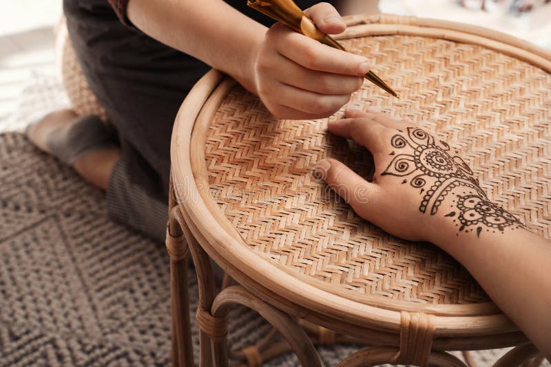 Mistrz robi tatuaż henny na rękach przy stole. tradycyjny mehndi