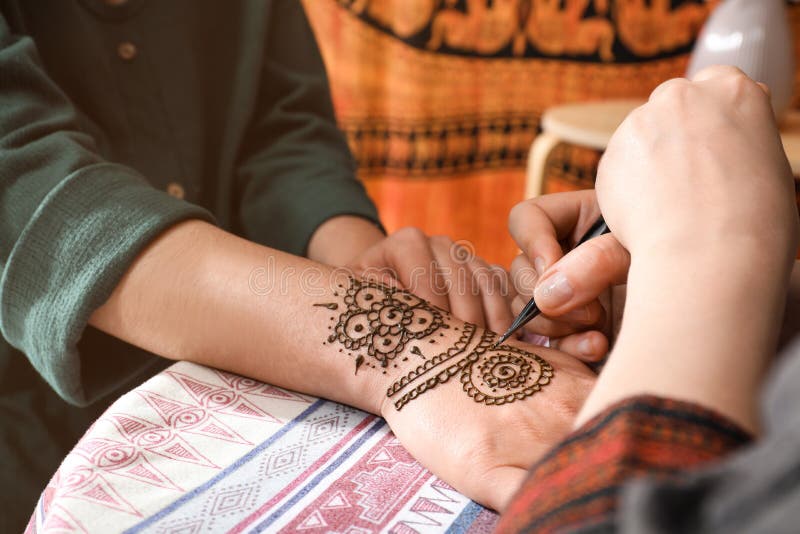 Mistrz robi tatuaż na dłoni. tradycyjny mehndi