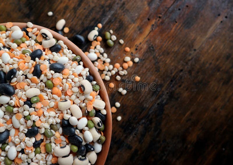 Mistura das leguminosa feitas dos feijões, da lentilha vermelha, do azuki verde e da cevada em uma bacia da terracota na madeira imagens de stock Mistura das leguminosa feitas dos feijões, da lentilha vermelha, do azuki verde e da cevada em uma bacia da terracota na madeira imagens de stock