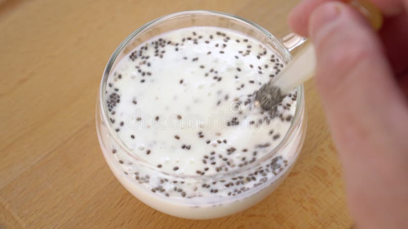 Mistura manual de iogurte grosso com colher de sobremesa com sementes de chia.