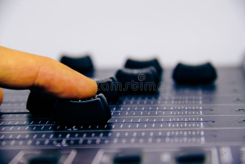 Misturador audio, controles de mistura da mesa e fader, console de mistura da música com a mão do técnico que move os faders degr imagem de stock Misturador audio, controles de mistura da mesa e fader, console de mistura da música com a mão do técnico que move os faders degr imagem de stock