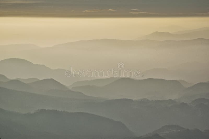 Misty Layers of Rolling Hills Under a Soft Golden Sky