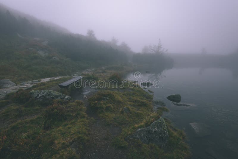 Mlhavé ráno pohled v mokré horské oblasti ve slovenských Tatrách. panorama horského jezera - vzhled vintage filmu