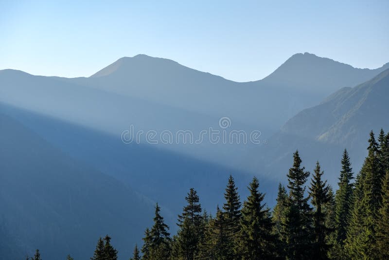 Misty sunrise in Slovakian Tatra mountains with light lanes in f