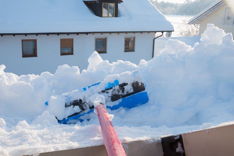 Mit der Schneeschuppe viel Schnee vom Dachfenster entfernen. Schneeflocken vom Dachfenster mit der Schneeschuhle entfernen. Landschaft zu Hause
