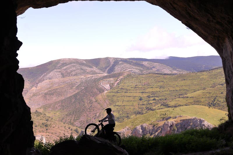 Mit einer Mountainbike in einer großen Höhle vor einem großen Tal stockbilder