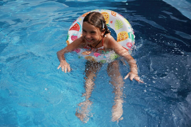 Mit Rettungsschwimmern schwimmen lernen. Glückliches kleines Mädchen macht Spaß am Pool stockfotos