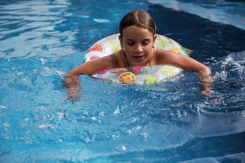 Mit Rettungsschwimmern schwimmen lernen. Glückliches kleines Mädchen macht Spaß am Pool lizenzfreies stockfoto