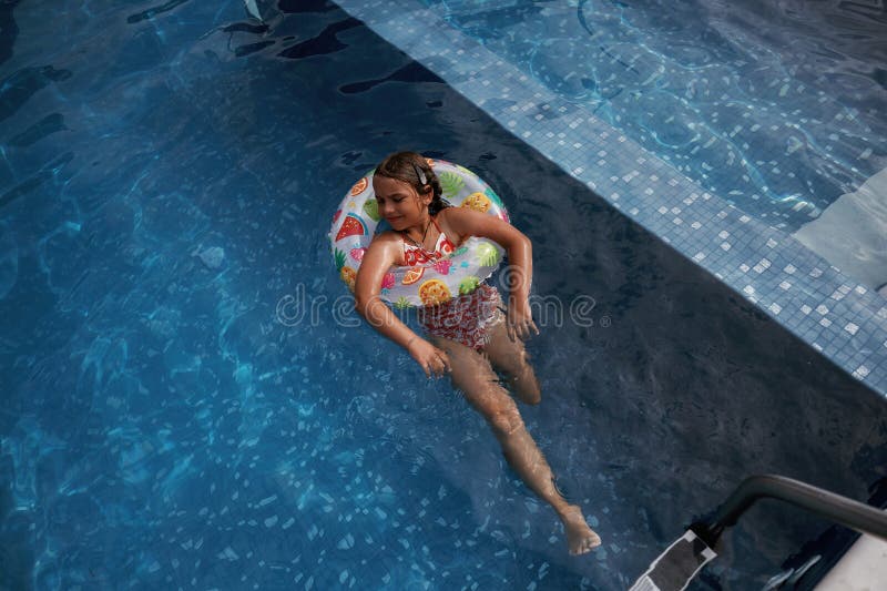 Mit Rettungsschwimmern schwimmen lernen. Glückliches kleines Mädchen macht Spaß am Pool lizenzfreies stockbild