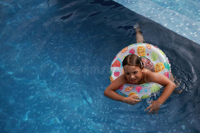 Mit Rettungsschwimmern schwimmen lernen. Glückliches kleines Mädchen macht Spaß am Pool stockbilder