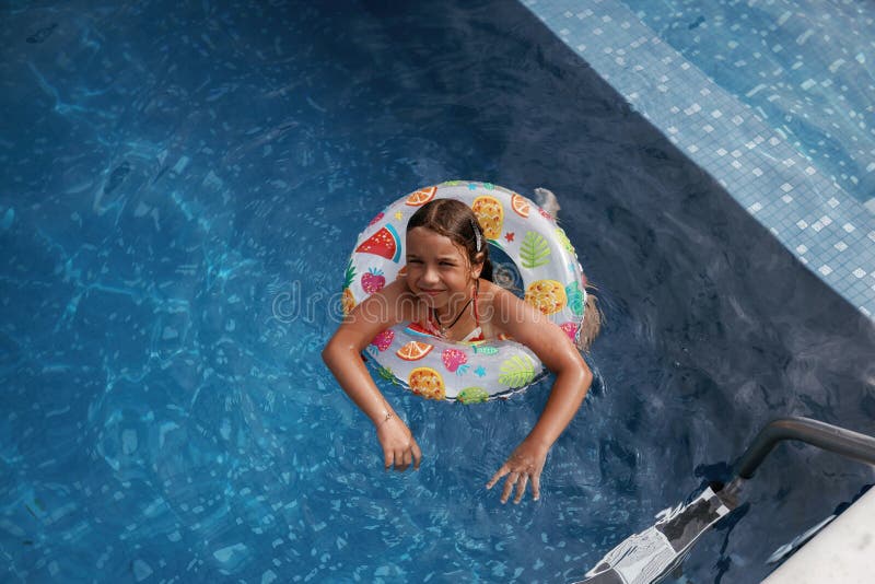 Mit Rettungsschwimmern schwimmen lernen. Glückliches kleines Mädchen macht Spaß am Pool stockfotografie