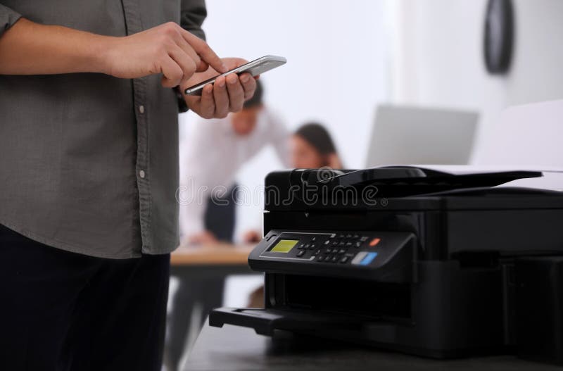 Employee using modern printer in office. Employee using modern printer in office