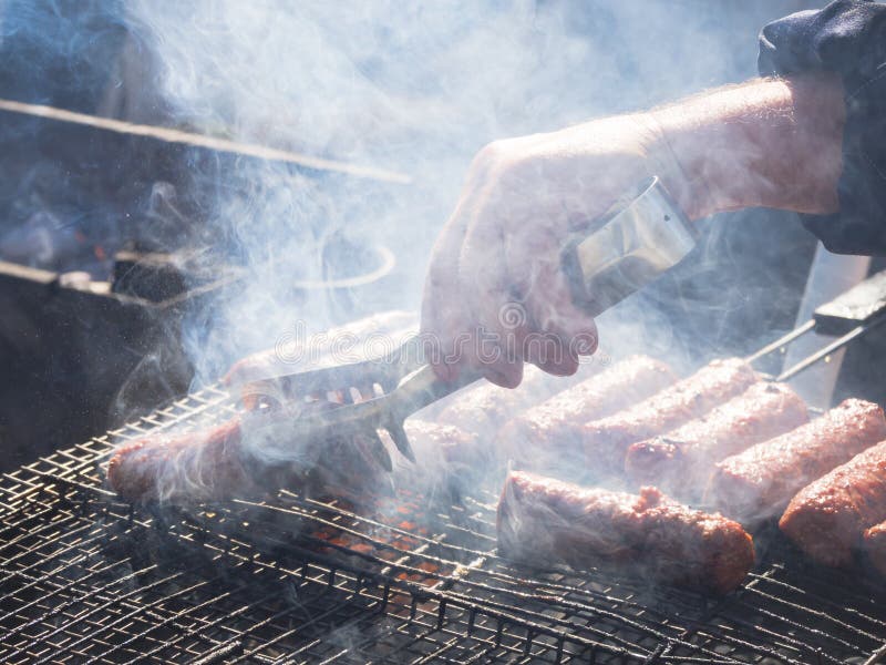Mititei rumeno e cucinato sulla griglia nel fumo immagini stock Mititei rumeno e cucinato sulla griglia nel fumo immagini stock
