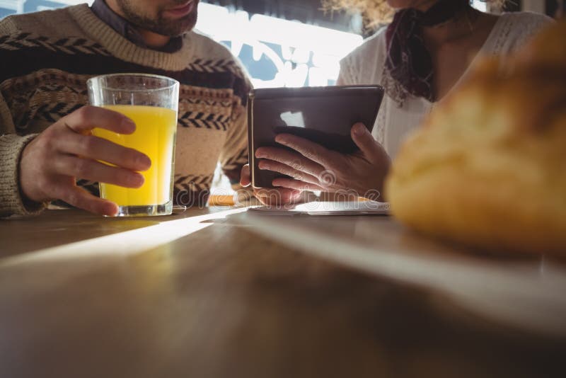 Mitt- avsnitt av kvinnan med mannen som använder minnestavlan i kafé royaltyfri fotografi Mitt- avsnitt av kvinnan med mannen som använder minnestavlan i kafé royaltyfri fotografi