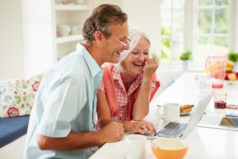 Mitte gealterte Paare, die Laptop über Frühstück betrachten stockfoto Mitte gealterte Paare, die Laptop über Frühstück betrachten stockfoto