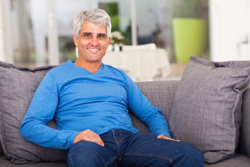 Cheerful middle aged man relaxing on sofa at home. Cheerful middle aged man relaxing on sofa at home