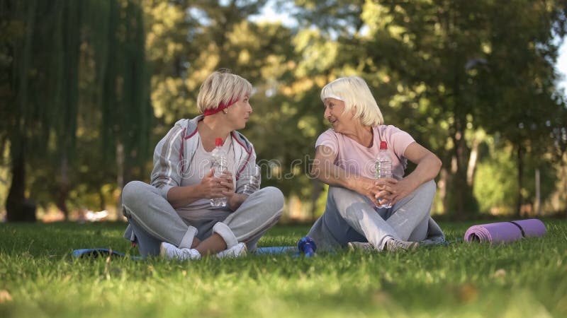 Mittelalterfrau und ihre Mutter, die nach dem Handeln von Übungen und von Yoga im Park sprechen stockbilder Mittelalterfrau und ihre Mutter, die nach dem Handeln von Übungen und von Yoga im Park sprechen stockbilder