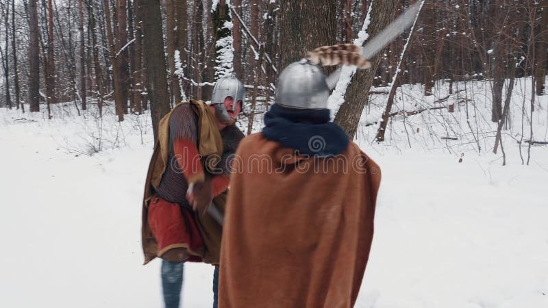 Mittelalterliche irische und frankish Krieger in der Rüstung kämpfend in einem Winterwald mit Klingen und Schildern