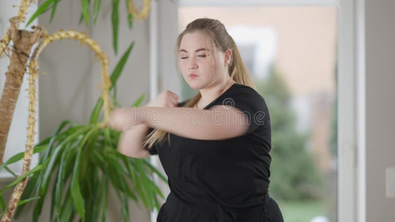 Mittlere Schuss Porträt von ernsthaften konzentrierten molligen Sportlerin Boxschatten drinnen. motivierter kaukasischer Jugendlic