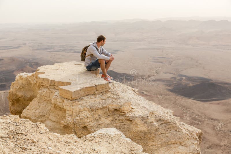 Man watching the horizon on the edge of Ramon crater cliff at  Negev desert, Israel