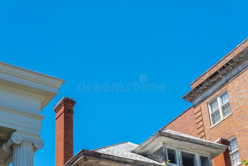 Mix of architecture with Ionic columns, abandoned house with very tall chimney, and brick apartment buildings royalty free stock images Mix of architecture with Ionic columns, abandoned house with very tall chimney, and brick apartment buildings royalty free stock images