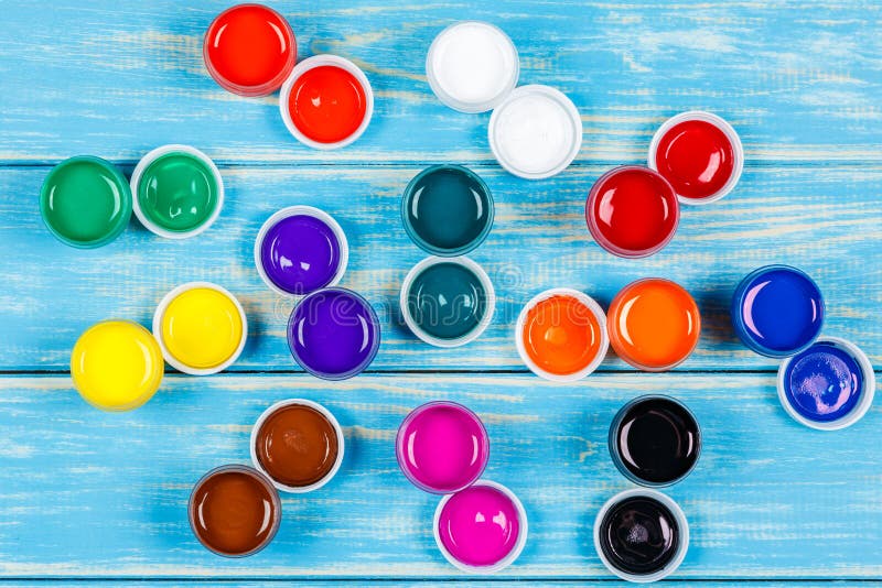 Open Cans of Colored Paint on the Blue Wooden Background Stock Photo