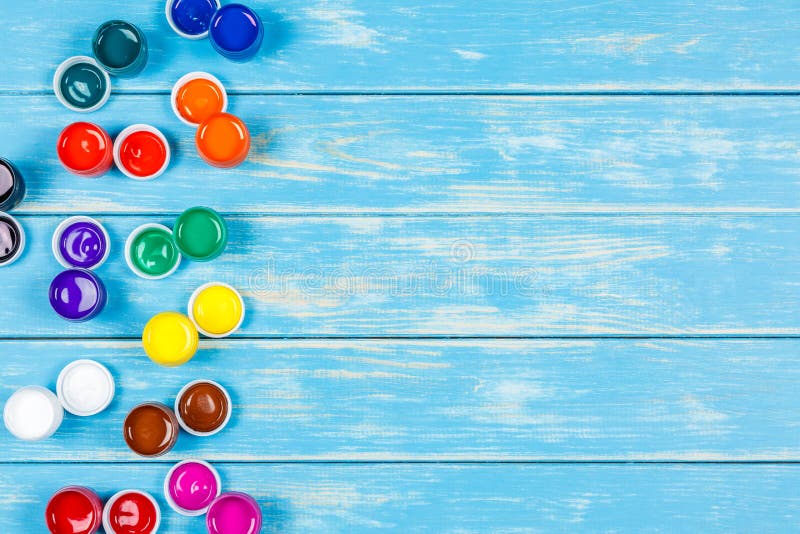 Mixed Open Cans of Paint on a Blue Wooden Background Stock Image